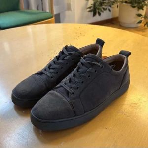 Louboutin gråa - Snygga mörkgrå sneakers i mocka med snörning. Perfekta för en stilren look. De har en klassisk design med rund tå och en bekväm sula.