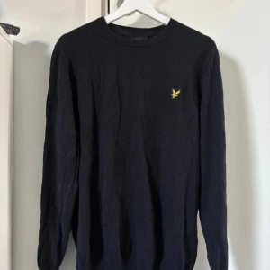 Svart tröja från Lyle & Scott - Säljer en stilren svart tröja från Lyle & Scott med deras ikoniska logga på bröstet. Tröjan är tillverkad i en blandning av bomull och ull, vilket gör den både bekväm och varm. Perfekt för kyligare dagar. Aldrig använd! Storlek XL. Inköpspris: 469 kr 