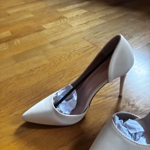 Beige pumps med spetsig tå - Eleganta beige pumps med spetsig tå och hög klack. Perfekta för en stilren look.