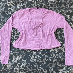 Lila ribbad tröja från Vero Moda - Säljer en lila ribbad tröja från Vero Moda med knytning framtill. Tröjan har långa ärmar och en avslappnad passform. Fungerar både som kofta och topp! Har ett litet hål under höger arm (se sista bilden)  men inget som märks eller påverkar helheten🌸i Passar till både fest och vardags🌸