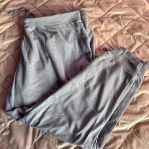 Grå mjukisbyxor med snörning - Säljer ett par grå mjukisbyxor med snörning i midjan. Byxorna har en avslappnad passform och är perfekta för en bekväm dag hemma. De är tillverkade i ett mjukt material som känns skönt mot huden. Öppen för prisförslag! 