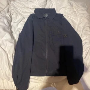 Mörkblå jacka från Lagency - Snygg mörkblå jacka från Lagency med dragkedja och knappdetaljer. Jackan har en klassisk krage och en diskret logotyp på bröstet. Perfekt för en stilren look. Använd två gånger 