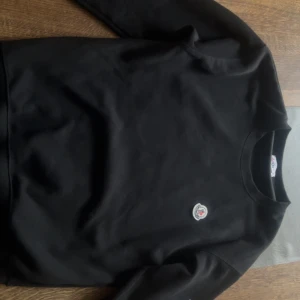 Svart sweatshirt från Moncler - Snygg svart sweatshirt från Moncler med rund hals och långärmade. Tröjan har Monclers logotyp broderad på bröstet och en stor M-logga i silver. Perfekt för en stilren look. Det finns Nfc Scan. Inget Kvitto