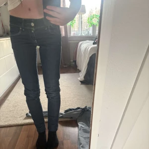 Mörkblå jeans med dragkedjedetaljer - Snygga mörkblå jeans med tight passform och coola dragkedjor på bakfickorna. Perfekta för en stilren look. De har en låg midja och klassisk femficksdesign.