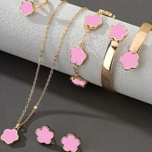 Guldfärgat smyckeset med rosa blommor - Elegant smyckeset i guldfärg med rosa blomdetaljer. Setet inkluderar ett halsband, armband, ring och örhängen, alla med matchande blommotiv. Perfekt för att lägga till en färgglad touch till din outfit.