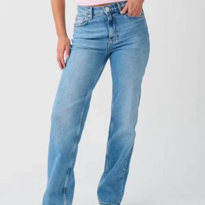 Blå jeans med rak passform - Snygga blå jeans med rak passform och klassisk design. De har en mellanhög midja och femficksmodell med knapp och dragkedja framtill. Perfekta för en avslappnad stil.