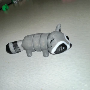 Grå tvättbjörn figur - Charmig liten grå tvättbjörn figur med svarta och vita detaljer. Figuren har en randig svans och är gjord i ett flexibelt material som kan böjas. Perfekt som dekoration eller leksak.