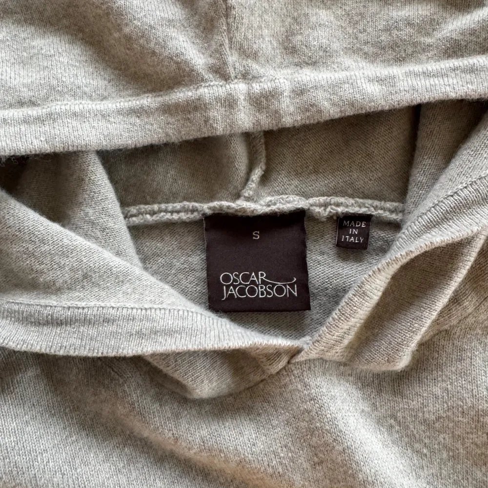 Säljer en stilren beige hoodie från Oscar Jacobson, tillverkad i Italien. Tröjan har en klassisk design med huva och ribbade muddar vid ärmslut och nederkant. Perfekt för en avslappnad och elegant look. Blend Cashmire 50/50. Bara att höra av sig till oss vid minsta fundering😁. Hupparit & Collegepaidat.