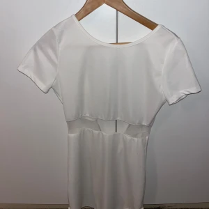Vit klänning från Acesnug - Snygg vit klänning från Acesnug med korta ärmar och en stilren design. Perfekt för en somrig look. Klänningen har en unik detalj i midjan som ger en modern touch. Passar xs/s aldrig använd