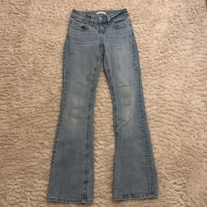 Ljusblå bootcut jeans från  Gina tricot - Snygga ljusblå bootcut jeans från Gina tricot. De har en klassisk femficksdesign med knappar och dragkedja framtill. Perfekta för en avslappnad stil med en touch av retro.