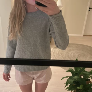 Grå stickad tröja från Vero Moda - Säljer en mysig grå stickad tröja från Vero Moda. Perfekt för kyligare dagar med sin mjuka och bekväma passform. Tröjan har långa ärmar och ribbade kanter vid ärmslut och nederkant. Passar perfekt till jeans eller kjol för en avslappnad look.