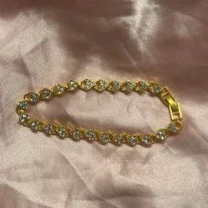 Guldarmband med glittriga stenar - Elegant guldarmband med gnistrande stenar i en rad. Armbandet har en säker låsning och en klassisk design som passar perfekt för speciella tillfällen. Perfekt för att lägga till en touch av glamour till din look. Super fin o säljs pga fel storlek. Helt ny 