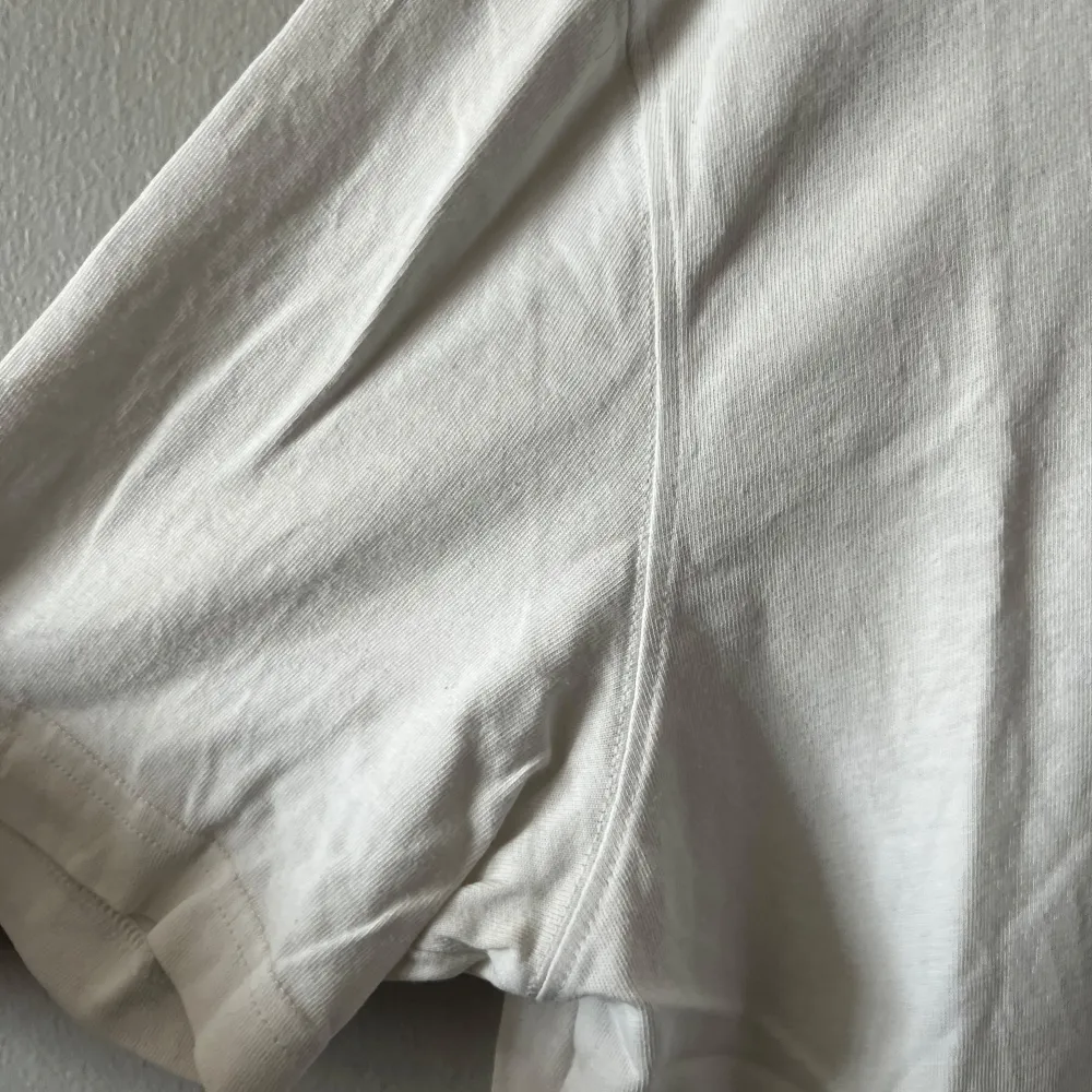 Säljer en klassisk vit t-shirt från Adidas med ett broderat sneaker-märke på bröstet. T-shirten är kortärmad och tillverkad i mjuk bomull. Perfekt för en avslappnad stil.. T-paidat.