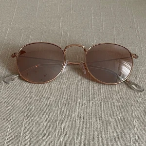  solglasögon rosé/guldfärgad  - Snygga runda solglasögon med guldfärgad metallram och bruna tonade glas.  Förekommer repor på glaset