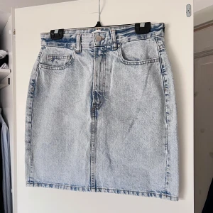 Ljusblå jeanskjol - Snygg ljusblå jeanskjol med klassisk femficksdesign och knappstängning fram. Perfekt för en avslappnad stil. Kjolen har en rak passform och är i en kort längd 🩵 Önskar du veta exakta mått? Tveka inte att höra av dig!