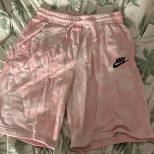 Rosa shorts från Nike - Säljer ett par rosa shorts från Nike med ett snyggt tryck av loggan byter färg från svart till grön när de blir varma.