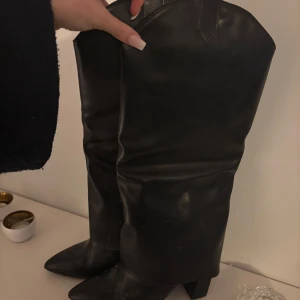 Svarta cowboy boots - Snygga svarta cowboy boots i skinn med klassisk design. Perfekta för en stilren look med spetsig tå och hög skaft. Passar utmärkt för både vardag och speciella tillfällen.
