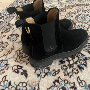 Svarta boots från Gant - Snygga svarta boots från Gant i mocka med elastiska paneler på sidorna och en praktisk dragflik. Nästan helt oanvända! Säljes pga fel storlek.