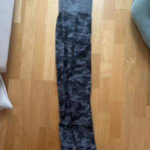 Grå camo leggings - Snygga grå leggings med camouflagemönster. Perfekta för en avslappnad stil eller träning. De har en tight passform och är gjorda i ett mjukt och stretchigt material. Finns tyvärr ett litet hål i scrunchen men i övrigt fina❤️