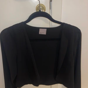 Svart kavaj från Vero Moda - Snygg svart kavaj från Vero Moda i storlek S. Perfekt för en stilren look med sin enkla design och långa ärmar. Passar utmärkt till både vardag och mer uppklädda tillfällen.