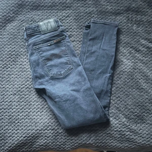 Mörkblå jeans från Nudie Jeans - Snygga mörkblå jeans från Nudie Jeans med en klassisk femficksdesign. De har en dragkedja och knapp framtill. Perfekta för en avslappnad stil med en modern touch. Skick 8/10✅ kontakta vid intresse/mer bilder🤩🤩 🚨snabb affär=lägre pris🚨