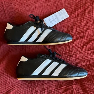 Adidas Taekwondo Lace W  - Otroligt snygga skor från Adidas, modell Taekwondo Lace. För kvinnor. Dom är som ni kan se helt nya och oanvända. Säljer då dom är för små för mig. Det är storlek 40 men jag skulle säga att dom passar 39 bättre. Erbjuder frakt men det går även bra att hämta på plats i Malmö.