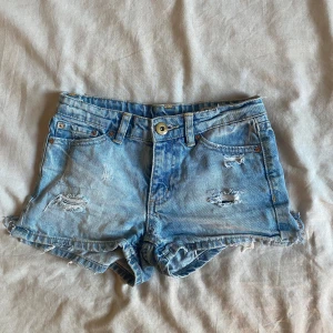 Ljusa jeansshorts med slitningar - Ljusblåa jeansshorts, Köpa på Plick med slitningar från förra ägaren, Storlek 140 originella märket är laget 157.Skriv för flera bilder eller frågor 💕🙌