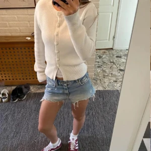 Vit kofta från Zara - Säljer en stilren vit kofta från Zara med dekorativa knappar framtill. Koftan har en rund halsringning och långa ärmar, perfekt för en elegant och enkel look. Passar bra till både jeans och kjol. Perfekt för vår och sommar!