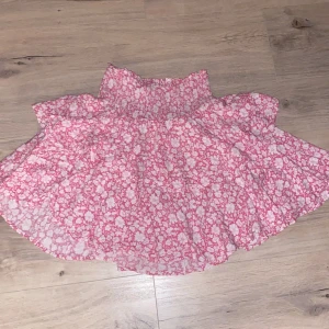 Rosa blommig kjol från Samsøe Samsøe - Charmig rosa kjol med blommigt mönster från Samsøe Samsøe. Kjolen har en elastisk midja för bekväm passform och en luftig design som ger en härlig sommarkänsla. Perfekt för varma dagar när du vill känna dig både söt och bekväm.