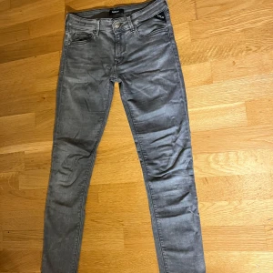 Replay anbass - Snygga grå jeans från Replay med en klassisk femficksdesign. De har en diskret logga på bakfickan och en knappgylf. Perfekta för en stilren look. De har jättebra skick!