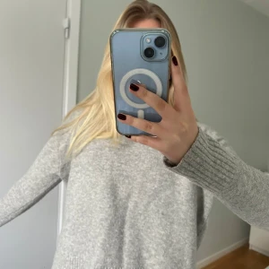 Grå stickad tröja - Mysig grå stickad tröja med rund hals och långa ärmar. Perfekt för kyligare dagar med ribbade detaljer vid ärmslut och nederkant. En klassisk och stilren design som passar till det mesta.