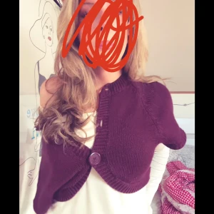 Vinröd/lila bolero - Säljer en vinröd bolerotopp med korta ärmar och knappar framtill. Perfekt för att lägga till en extra touch till din outfit. Passar bra över en topp eller klänning.