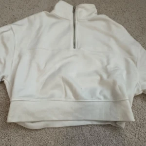 Vit halvzip sweatshirt från H&M - Säljer en vit sweatshirt med halv dragkedja och hög krage från H&M. Tröjan har långa ärmar, ribbade muddar och är tillverkad i mjuk bomullsmix. Perfekt för en avslappnad och stilren look.