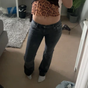 Svarta jeansbyxor med bootcut - Säljer ett par mörkgrå jeansbyxor med klassisk femficksdesign och bootcut passform. Byxorna har låg midja och stängs med dragkedja och knapp framtill. Perfekta till vardags för en avslappnad stil.