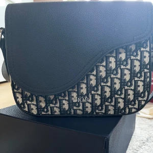 Svart och beige axelväska  - Säljer en snygg axelväska som har både mycket bra utrymme och design. Med köpet tillkommer boxen och dustbagen. Mått kan skickas i dm och är öppen för nya prisförslag.
