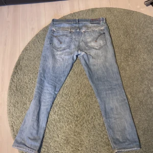 Dondup jeans george  - Säljer ett par ljusblå skinny jeans från dondup. Jeansen har slitna detaljer framtill och klassisk femficksdesign. Passformen är skinny fit och de är tillverkade i ett mjukt denimtyg. Perfekta för dig som gillar en smal siluett. Jag har sytt ihop byxorna (det ser ni på bilden) men när man har på sig dem så ser man det inte.