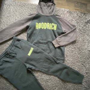 Grå hoodie från Hoodrich med matchande byxor - Säljer en grå hoodie från Hoodrich med neongul logga på bröstet och matchande mjukisbyxor. Hoodien har huva och magficka.. Perfekt för chill dagar. Använd 1-2 gånger! Kan även säljas separat om man inte vill ha både byxor och hoodie.