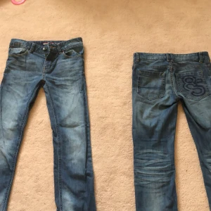 Blå jeans från Tommy Hilfiger - Säljer två par klassiska blå jeans från Tommy Hilfiger med normal passform. Jeansen har fem fickor, dragkedja och knapp framtill. Perfekta för en avslappnad stil. Vid intresse till att köpa endast ett par är det bara att höra av sig till mig 👍