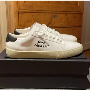 Saint Laurent skor - Säljer ett par vita saint Laurent skor. Ser väldigt bra ut efter en tvätt. Det man märker är att skorna är något creasade. Hör av dig vid intresse eller frågor😁👊!