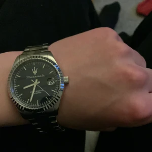Silverfärgad klocka från Maserati - Stilren klocka från Maserati med silverfärgat armband i metall och svart urtavla. Klockan har datumvisning och tydliga indexmarkeringar. Perfekt accessoar för dig som gillar klassisk design och italiensk känsla.