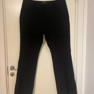 Lågmidjade svarta kostymbyxor från Bik Bok - Lågmidjade svarta kostymbyxor från Bik Bok med klassisk passform och raka ben. Byxorna har hällor för bälte, diskreta fickor och en liten slits vid benslutet. Perfekta för en stilren look. Små i storlek!!