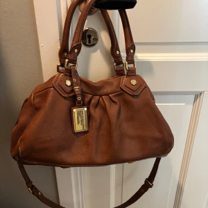 Marc Jacobs väska baby groove  - Säljer min fina bruna Marc Jacobs väska i den mellanstora modellen💘Fint skick och perfekt till tex skolan!! Modellen heter baby groove💘