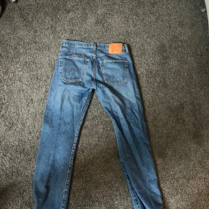 Levi's 501 blå jeans W31 L32 - Klassiska blå Levi's 501 jeans med raka ben och femficksdesign. Jeansen har normal passform och är tillverkade i slitstarkt material