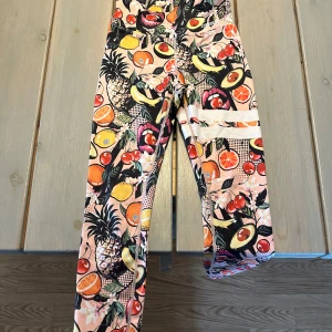 Färgglada träningstights med fruktmönster från Stronger - Säljer ett par färgglada träningstights från Stronger i storlek XS. Knappt använda, max 4 gånger.