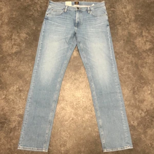 Ljusblå Lee Daren Zip Fly jeans - Säljer ett par ljusblå jeans från Lee, modell Daren Zip Fly. Klassisk femficksdesign med dragkedjegylf och raka ben. Jeansen har en snygg tvätt och är tillverkade i bomull. Perfekta för dig som gillar en tidlös stil.