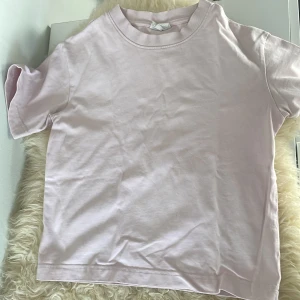 Ljusrosa basic t-shirt från Gina Tricot - En ljusrosa basic t-shirt från Gina Tricot, modell Basically Basics. T-shirten har rund halsringning och korta ärmar. Perfekt till jeans eller shorts för en enkel och clean look.