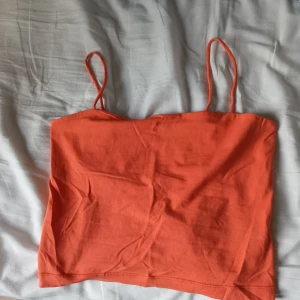 Korallfärgad croppad linnetopp - Säljer en korallfärgad croppad linnetopp med tunna axelband. Perfekt för varma dagar och enkel att matcha med jeans eller kjol.