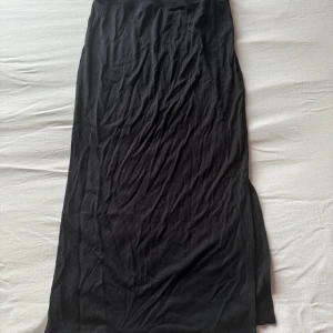 Svart tajt ribbad långkjol - Säljer en svart tajt långkjol med ribbad struktur och slits. Aldrig använt då den var för stor