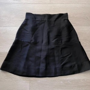 Svart kjol med utsvängd form - Säljer en svart kjol med utsvängd passform och hög midja. Kjolen är enkel och stilren, perfekt att matcha med olika toppar. Materialet känns mjukt och följsamt. Passar dig som gillar klassiska plagg med en modern twist.