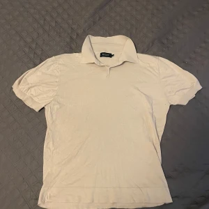 Beige pikétröja från Riley - Säljer en stilren beige pikétröja från Riley med klassisk krage och korta ärmar. Tillverkad i mjuk bomulls- och viskosblandning som känns skön mot huden. Perfekt för en avslappnad men ändå uppklädd look.